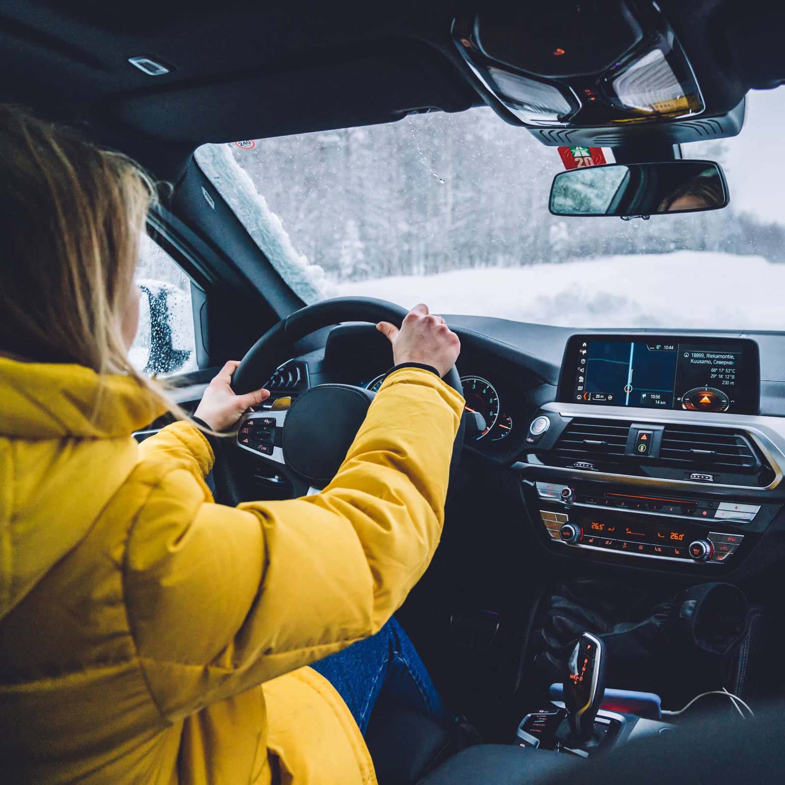 Driver wearing a yellow coat driving through winter conditions.