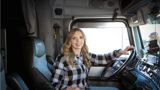 Female driver, Susie De Ridder, behind the wheel of her semi-truck.